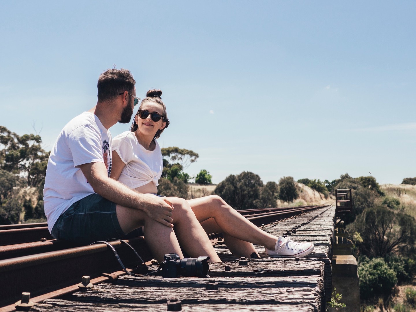 Couple sitting outdoors on abandoned railway line Couple sitting outdoors on abandoned railway line