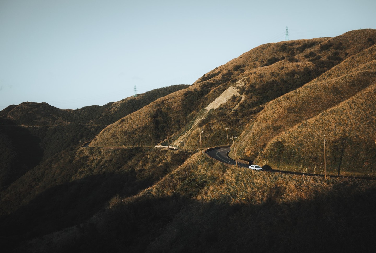 A car in the distance driving on a hilly road