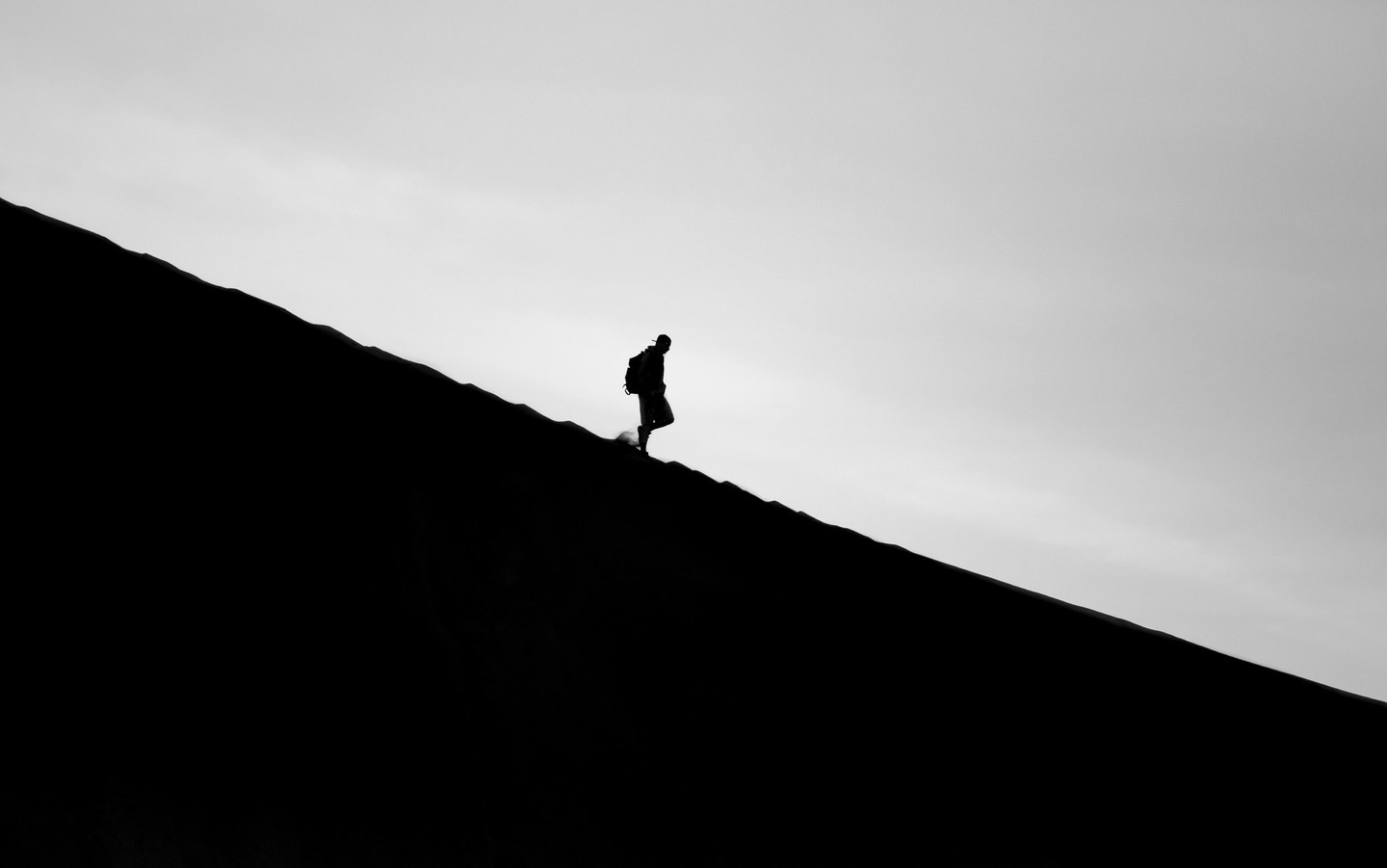 Silhouette of a man walking downhill