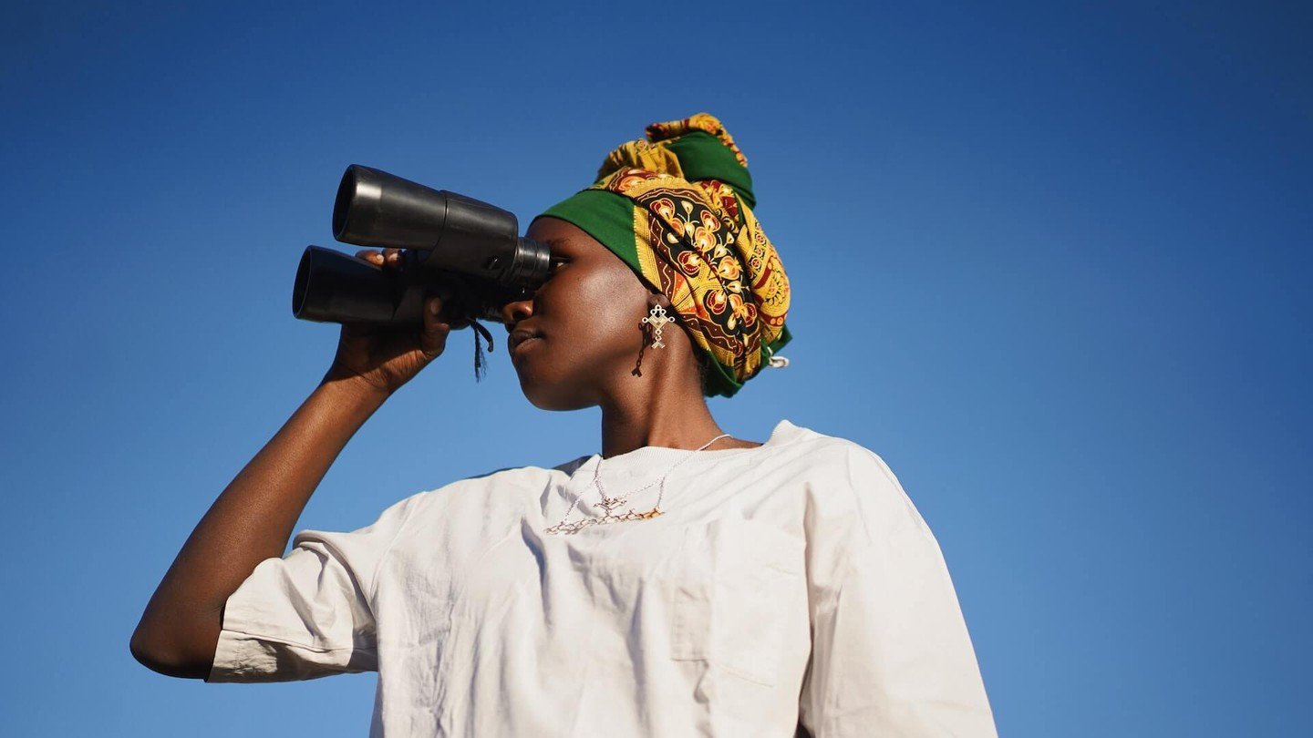 Woman in a white t-shirt looking through binoculars