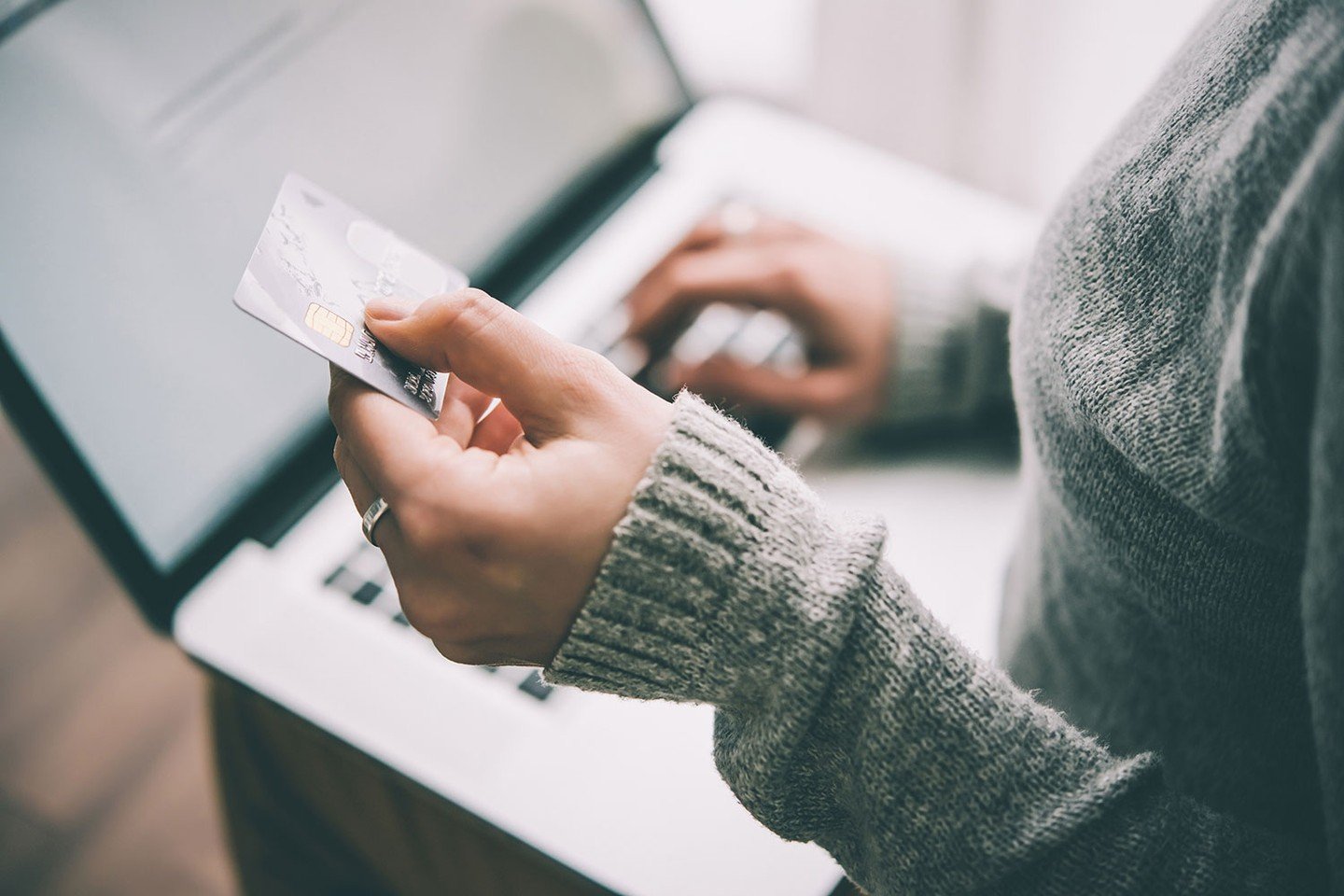 Person looking at credit card with laptop Person looking at credit card with laptop