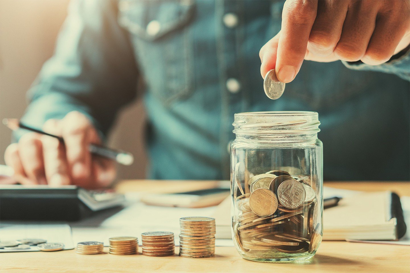 Man dropping coin into jar