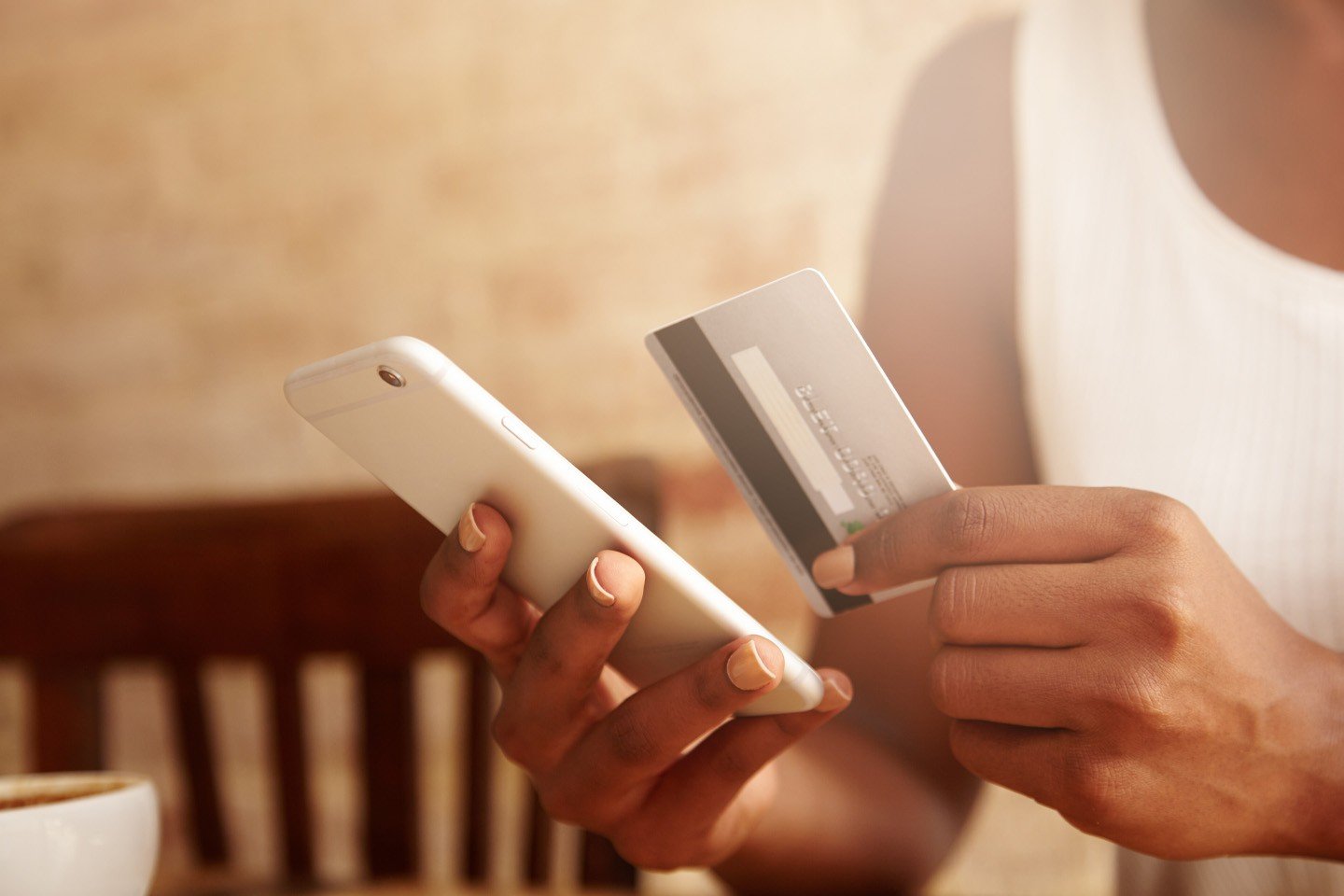 A person looks at their credit card, while holding their phone. 