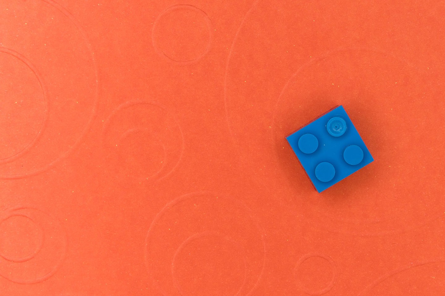 Single blue lego on orange background