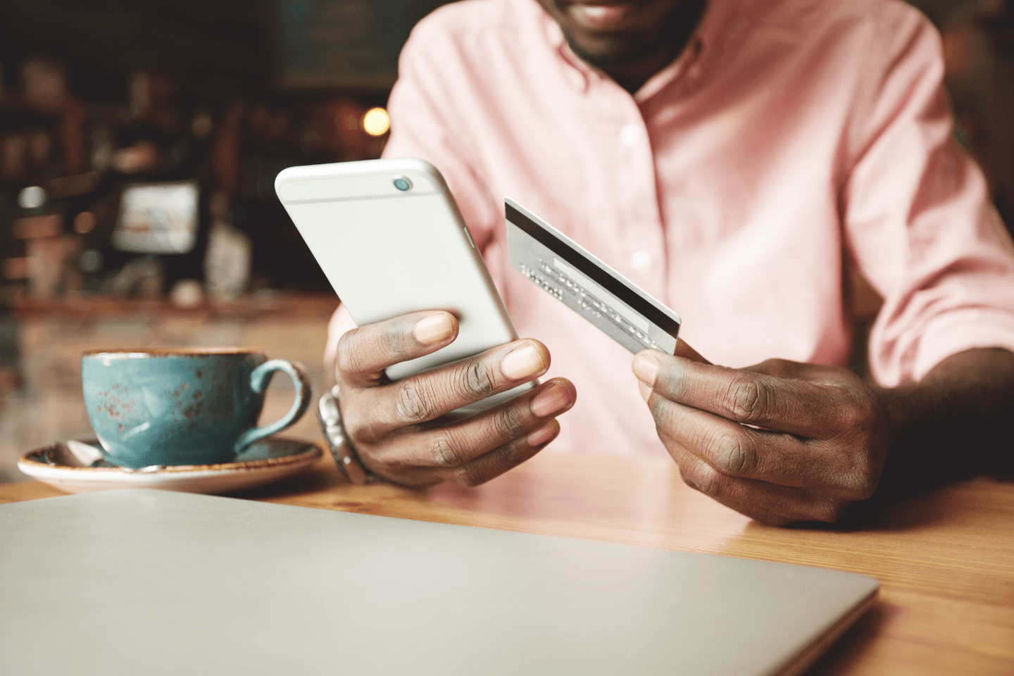 Man holds credit card while looking at his phone